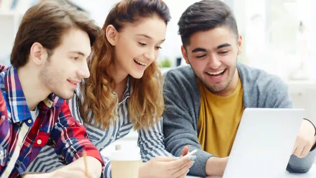 Tre studenti stanno utilizzando internet per trovare corsi online per imparare l'inglese.