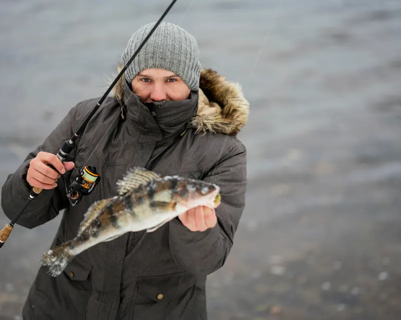Uomo che regge un pesce appena pescato con canna da pesca — curiosità sull'Inghilterra, il Salmon Act 1986