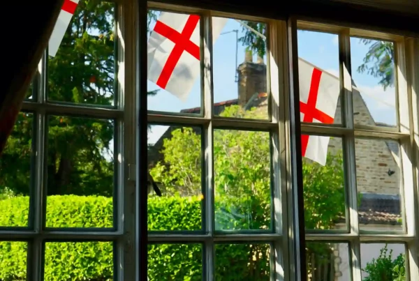 Simboli della cultura inglese visti da una finestra: bandiera della croce di San Giorgio, giardino curato e paesaggio rurale tipico