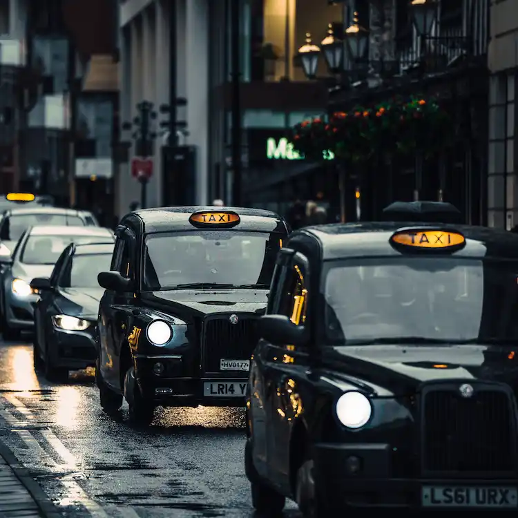 I tradizionali taxi neri di Londra (black cabs) in fila nel traffico cittadino su una strada bagnata, tra i simboli inglesi più famosi della cultura britannica.