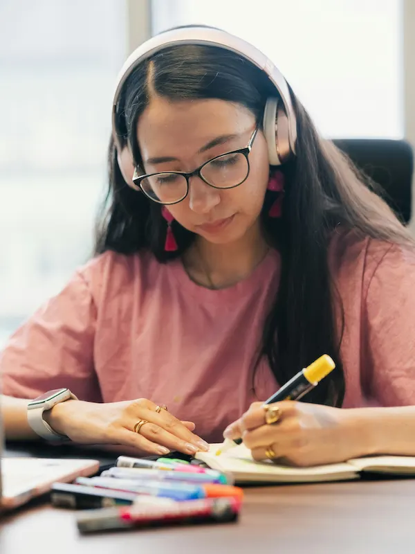 Ragazza con le cuffie che studia e prende appunti: impara l'inglese dormendo solo dopo un intenso studio attivo durante il giorno