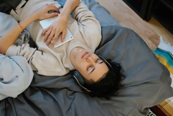Ragazzo che dorme con le cuffie e un tablet sul petto mentre cerca di imparare l'inglese dormendo