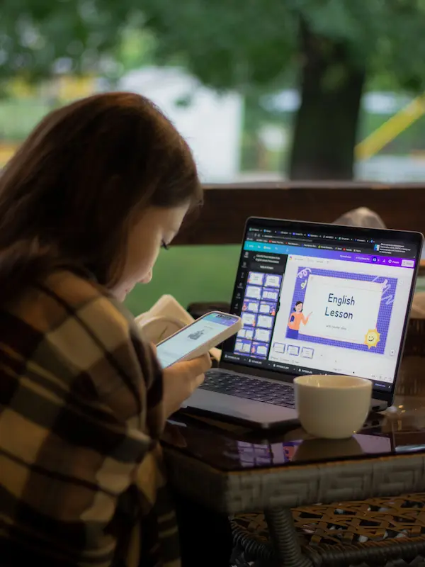 Ragazza studia inglese consultando smartphone e laptop con una lezione di inglese aperta sullo schermo