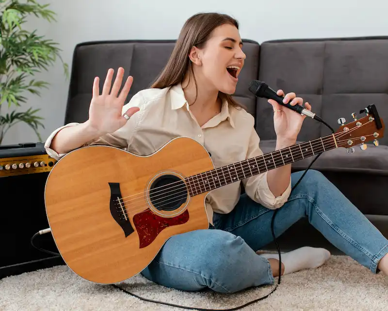 Ragazza sorridente canta al microfono suonando la chitarra, mentre impara l'inglese con le canzoni