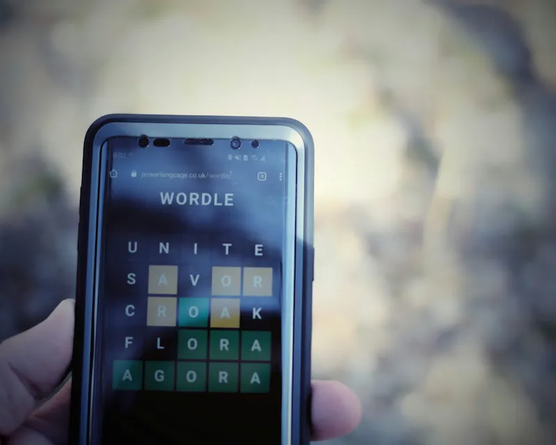 Smartphone tenuto in mano con il gioco Wordle aperto sullo schermo per imparare l'inglese.
