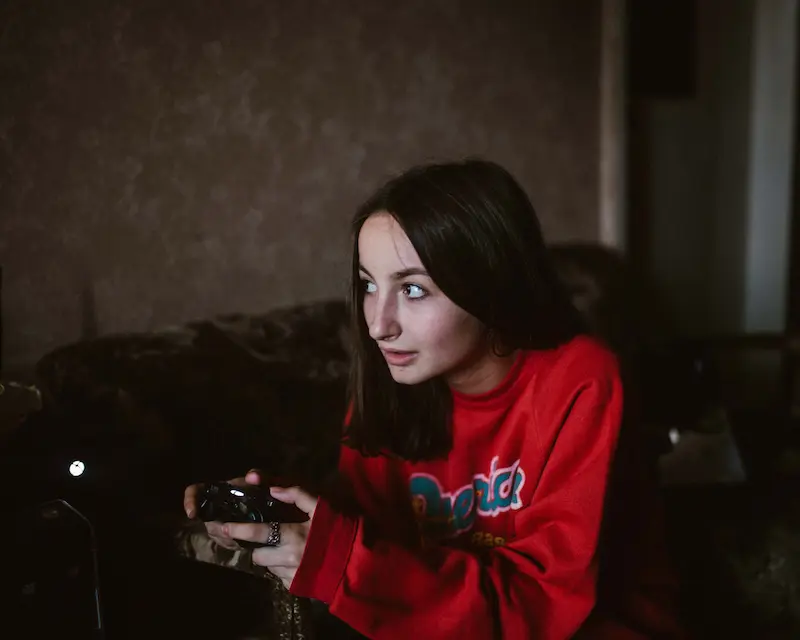 Una ragazza adolescente gioca a un videogioco con un controller in mano per esercitarsi con la lingua inglese.